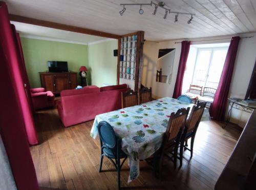 un salon avec une table et un canapé rouge dans l'établissement Grande maison dans la cité médiévale de Besse, à Besse-et-Saint-Anastaise