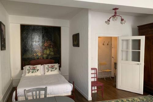 a bedroom with a bed and a painting on the wall at Studio sur les remparts Semur-en-Auxois BOURGOGNE in Semur-en-Auxois