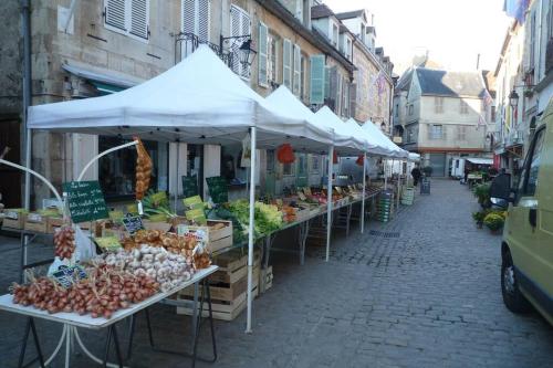 a street with a fruit and vegetable market with umbrellas at Studio sur les remparts Semur-en-Auxois BOURGOGNE in Semur-en-Auxois