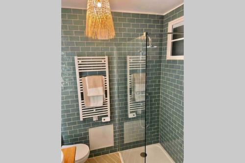 a bathroom with green subway tiles and a shower at Superbe appartement en pierre fraîchement rénové in Bernis
