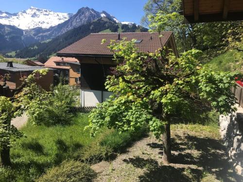 a house with a tree and mountains in the background at Apartment Haldematt by Interhome in Adelboden