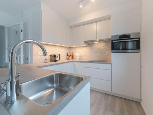 a kitchen with white cabinets and a stainless steel sink at Apartment Medano with balcony by Interhome in Bredene