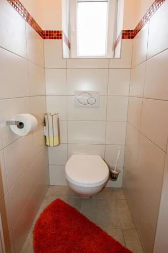 a bathroom with a toilet with a red rug and a window at Apartment Appartement Anja by Interhome in Saalfelden am Steinernen Meer