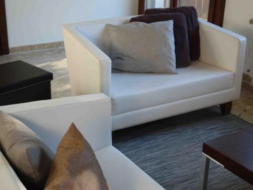 a white chair with pillows on it in a living room at Apartment Près du Bahnhof by Interhome in Engelberg