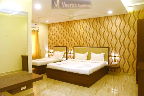 a hotel room with two beds and a mirror at Veeras Residency in Pondicherry