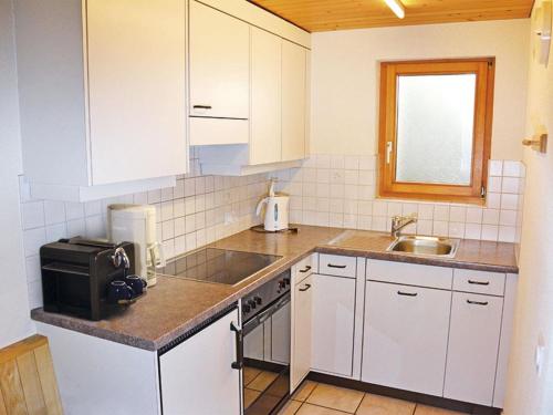 cocina con armarios blancos, fregadero y microondas en Apartment Marielle by Interhome, en Adelboden