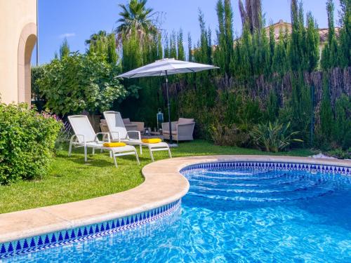 uma piscina com duas cadeiras e um guarda-sol em Villa Bellevie by Interhome em Oliva
