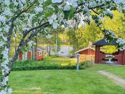 a yard with a cabin and a tree with white flowers at Holiday Home Polkurinne by Interhome in Saarijärvi