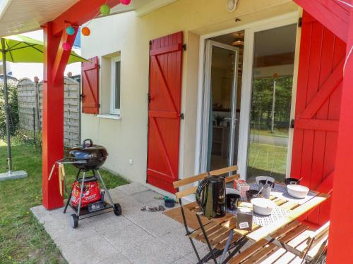 a patio with a red door and a table with a grill at Apartment Les Jardins de l'Océan by Interhome in Bias