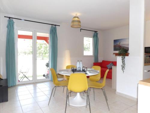 a dining room with a table and yellow chairs at Apartment Les Jardins de l'Océan by Interhome in Bias
