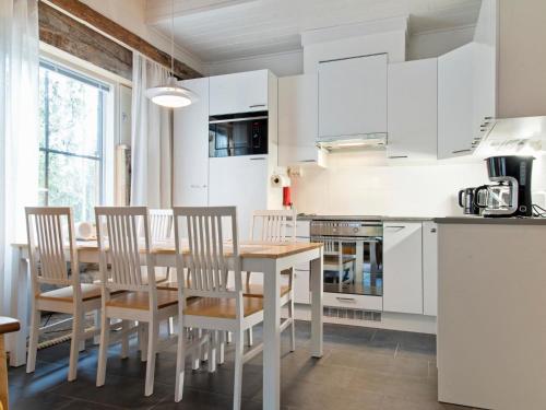 a kitchen with white cabinets and a wooden table and chairs at Holiday Home Taruilevi 10 j2 by Interhome in Sirkka