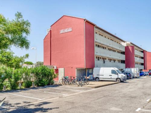 un bâtiment rouge avec des vélos garés dans un parking dans l'établissement Apartment Le Marlin by Interhome, au Grau-du-Roi