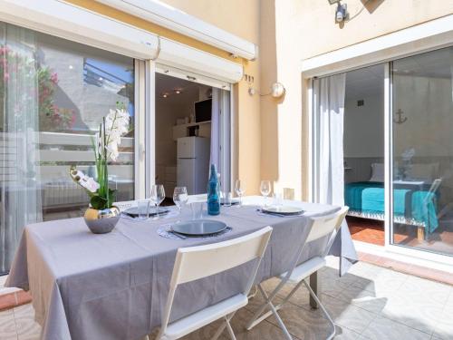 Apartment Les Cabestans 1-2-3-4 by Interhome في لو باركار: طاولة طعام مع قماش الطاولة الزرقاء والكراسي البيضاء