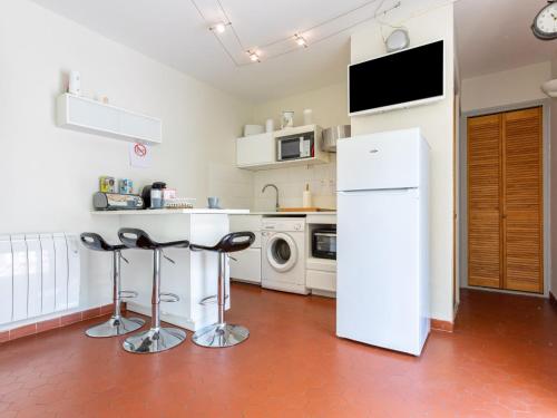 - une cuisine avec un réfrigérateur blanc et deux tabourets de bar dans l'établissement Apartment Les Cabestans 1-2-3-4 by Interhome, au Barcarès