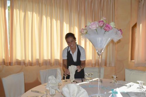 a woman is standing at a table in a restaurant at Hotel Giardino Corte Rubja in Iglesias