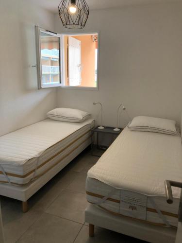 deux lits dans une chambre avec une fenêtre dans l'établissement Apartment Newly Renovated Aircond-wifi-pool-sea View-150m to Beaches- Saint Aygulf, à Saint-Aygulf