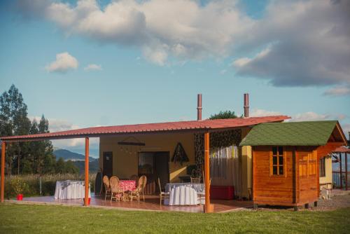 a cabin with a table and chairs on a deck at Hotel Reserva Campestre LA CABAÑA GLAMPING in Duitama