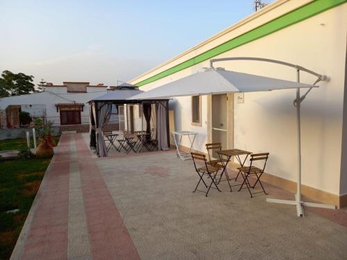 un patio con tavolo, sedie e ombrellone di Green Sea Bed & Breakfast a Elena Marina