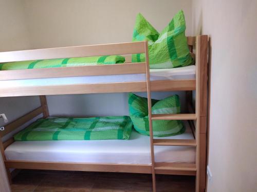 a bunk bed with green pillows on the bottom bunk at Untere Ferienwohnung Asshoff in Ahorn in Berolzheim