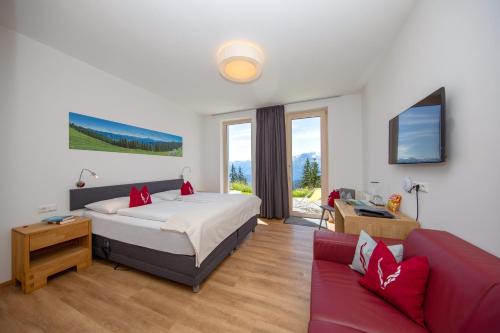 ein Schlafzimmer mit einem Bett und einem roten Sofa in der Unterkunft Schmiedhof Alm in Zell am See