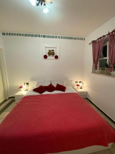 a bedroom with a red bed with two red pillows at Apartments Atila in Mali Lošinj