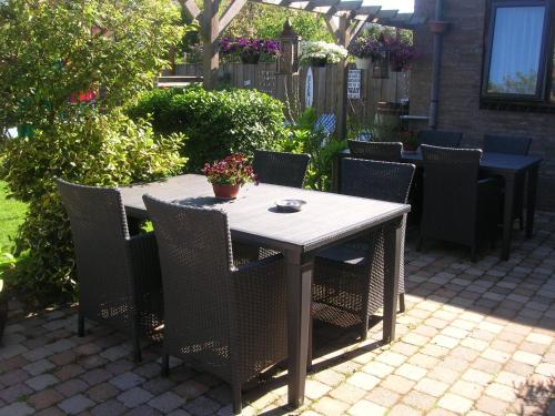 una mesa de madera y sillas en un patio en Pension Brinkvis, en De Koog