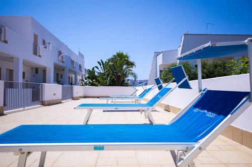 a row of blue lounge chairs on a swimming pool at Donnosanto Residence in Torre Santa Sabina