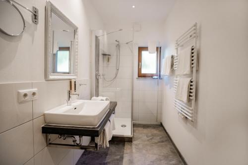 La salle de bains blanche est pourvue d'un lavabo et d'un miroir. dans l'établissement Der Lärchenhof Ferienwohnungen, à Schönau am Königssee