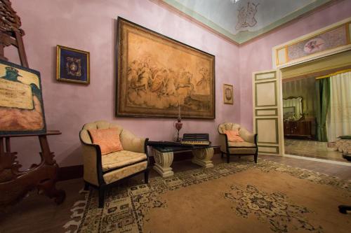a living room with two chairs and a painting on the wall at Meliaresort Dimore Storiche in Mazara del Vallo