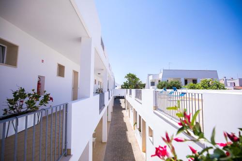 a balcony of a building with white walls and flowers at Donnosanto Residence in Torre Santa Sabina