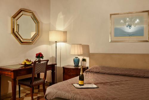 a hotel room with a bed and a desk with a bottle of champagne at Anzolo Palace - Rooms & Apartments in Venice
