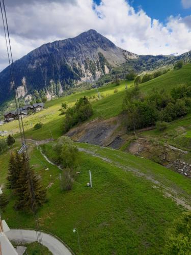 a green field with a mountain in the background at T2 vue piste Résidence Vostok Zodiaque in Le Corbier