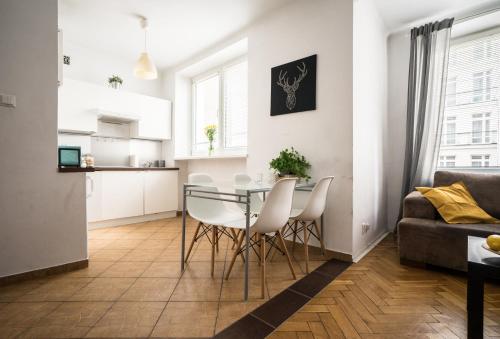 eine Küche und ein Wohnzimmer mit einem Glastisch und weißen Stühlen in der Unterkunft oompH Warsaw Modern Apartment near Nowy Świat in Warschau