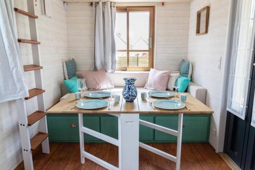 une table dans une petite maison avec des plaques bleues et blanches dans l'établissement Tiny house en Baie du Mont-Saint-Michel, à Dol-de-Bretagne