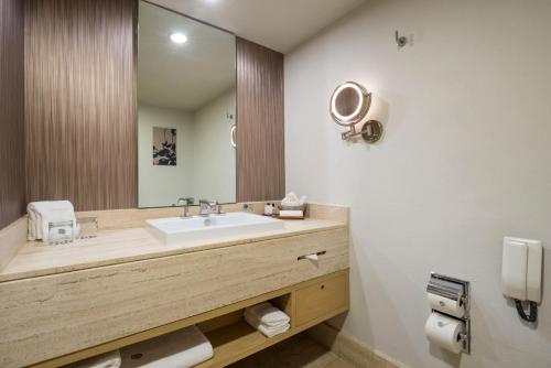ein Badezimmer mit einem Waschbecken und einem großen Spiegel in der Unterkunft Galeria Plaza Reforma in Mexiko-Stadt