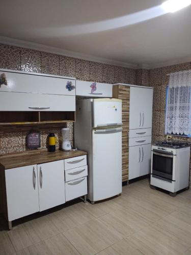 a kitchen with white appliances in a room at Triplex Costazul Temporada in Rio das Ostras