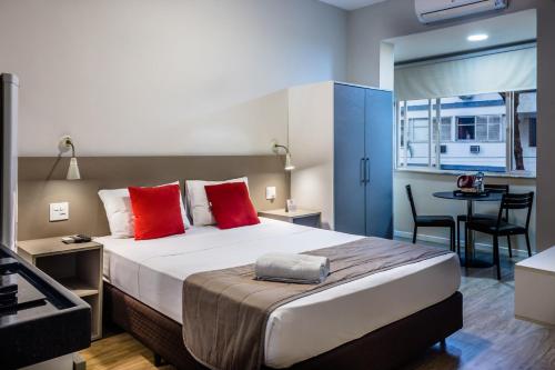 1 dormitorio con 1 cama grande con almohadas rojas en Injoy Lofts Ipanema, en Río de Janeiro