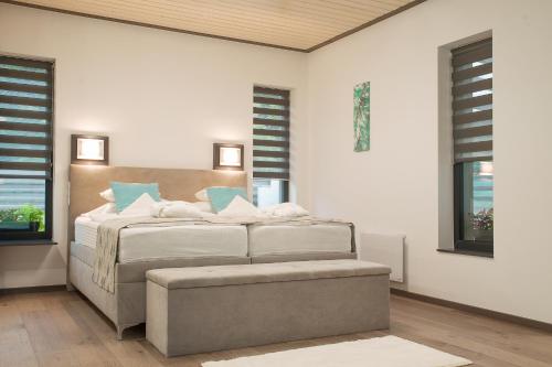 ein Schlafzimmer mit einem Bett mit einer Ottomane daneben in der Unterkunft Dunazug Plusz Luxus Apartman in Dömös