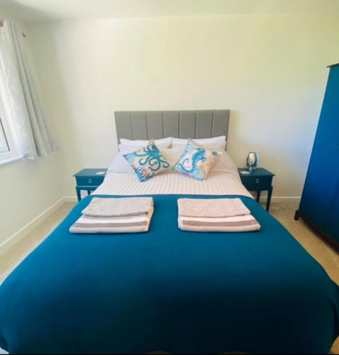 uma cama azul com três toalhas em cima em Eagle House Holiday Let em Bude