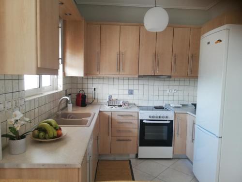 una cocina con armarios de madera y un bol de fruta en la barra en Luxury Apt Near The Airport, en Spáta