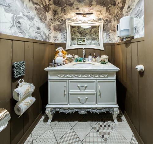 ein Badezimmer mit einem weißen Waschbecken und einem Spiegel in der Unterkunft Grand Sova in Plyos