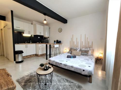 a bedroom with a large bed and a kitchen at Le Jasmin des Carmes - Hypercentre - Netflix in Toulouse