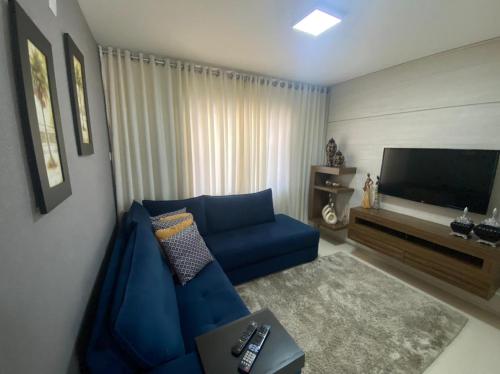 a living room with a blue couch and a flat screen tv at Casa Temporada da Jojo in Capitólio