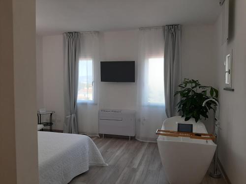 a white bedroom with a bed and a tv at B&B da Baba in Ghizzano