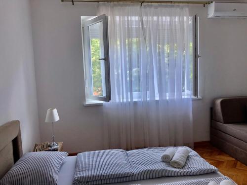 a bedroom with a bed with a window and a couch at Apartment Bregovi in Trebinje