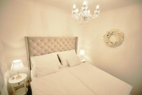 a bedroom with a white bed and a chandelier at Wine Apartments in Vráble