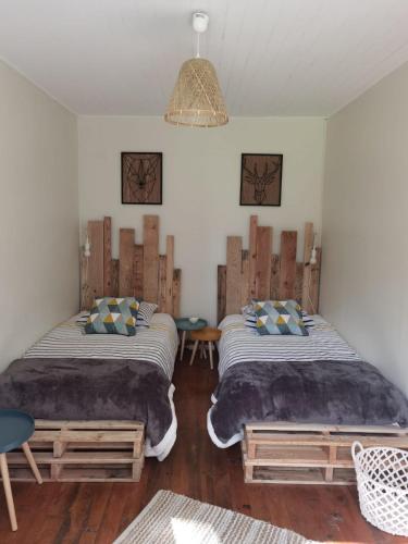 une chambre avec deux lits et un lustre dans l'établissement A la croisée des chemins, à Saint-Nicolas-des-Biefs