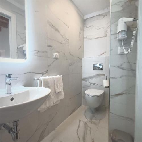 a white bathroom with a sink and a toilet at Lido di Alghero Beach Resort - La Villetta in Alghero
