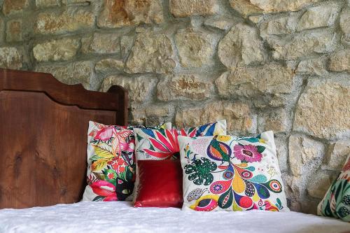 a pile of pillows on a bed with a stone wall at Caserio Urikosolo in Bilbao