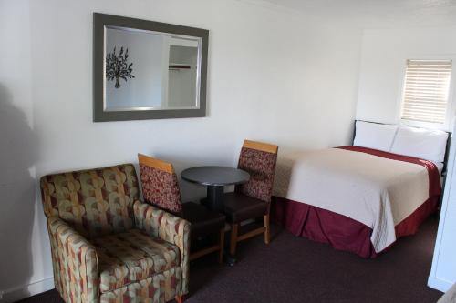 a room with a bed and a chair and a mirror at Chalet Motel - Affordable Stay in Central Bend in Bend
